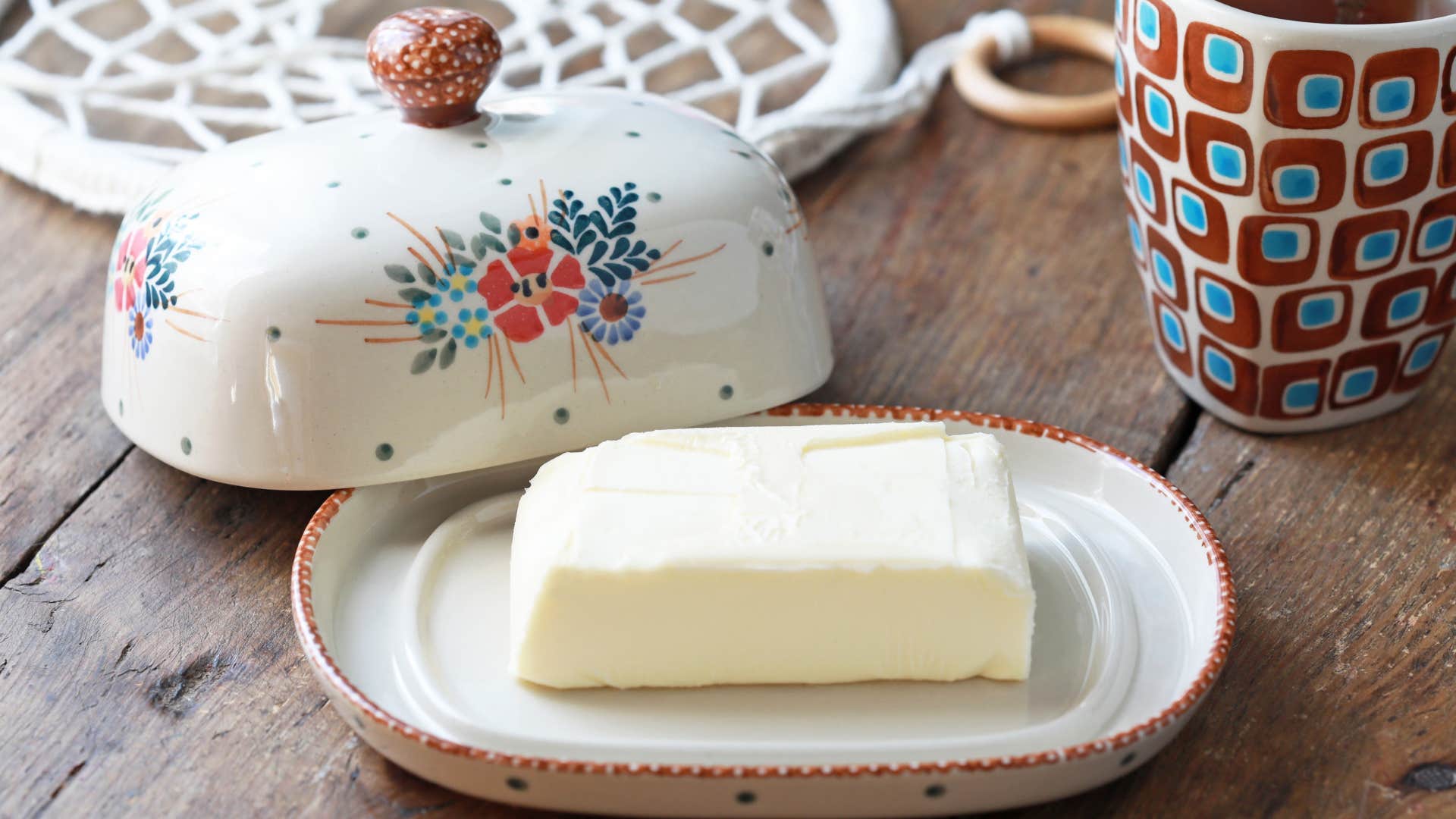 butter dish on wood table with cup nearby