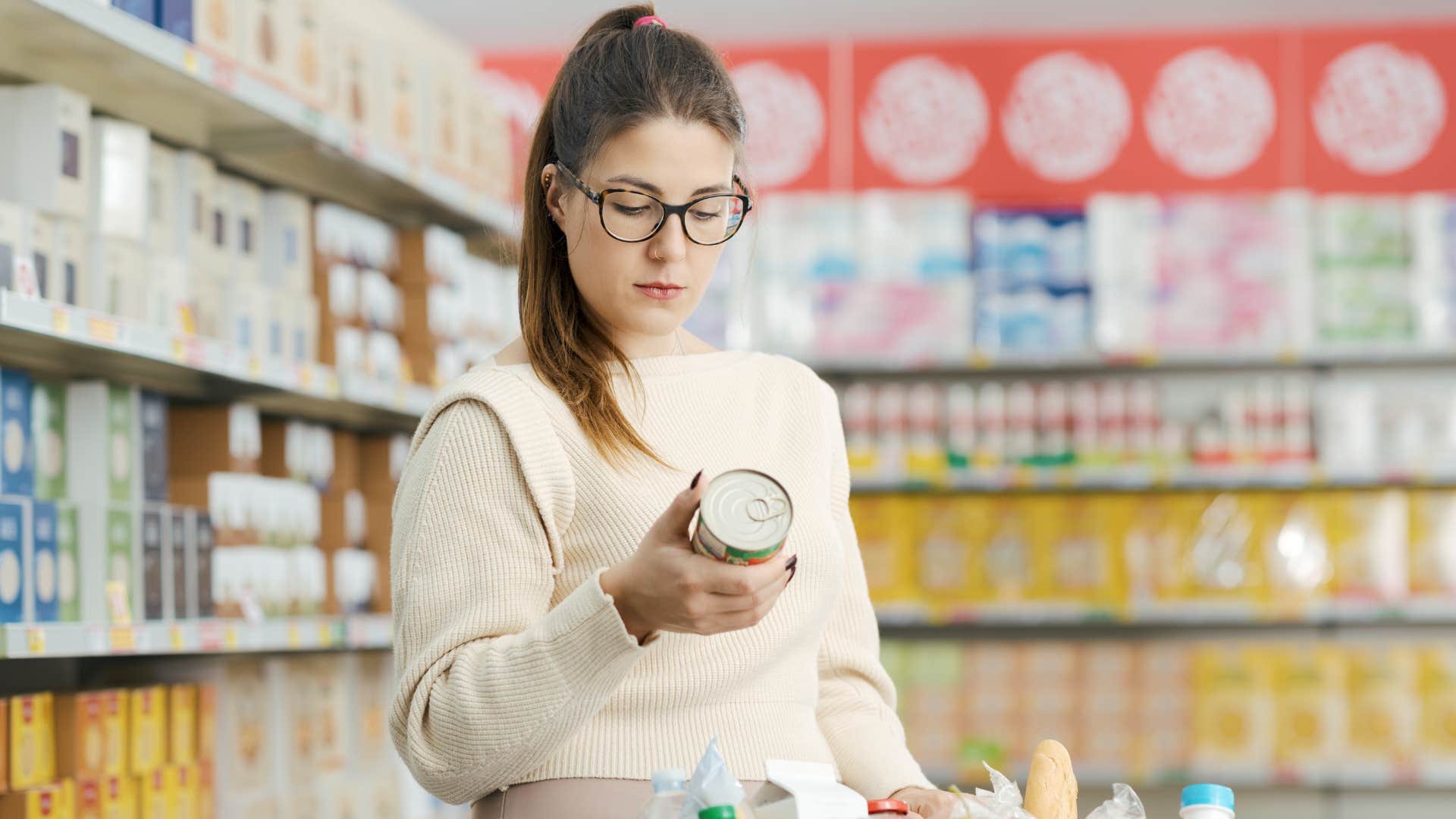 woman in glasses and white shirt holding can noticing she doesn't need an electric can opener