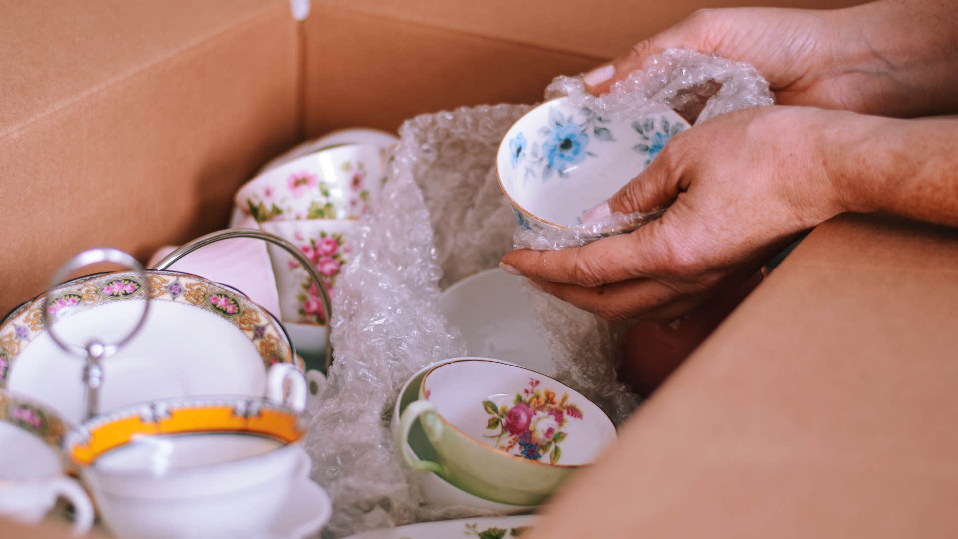 woman taking out fancy china cabinets from box