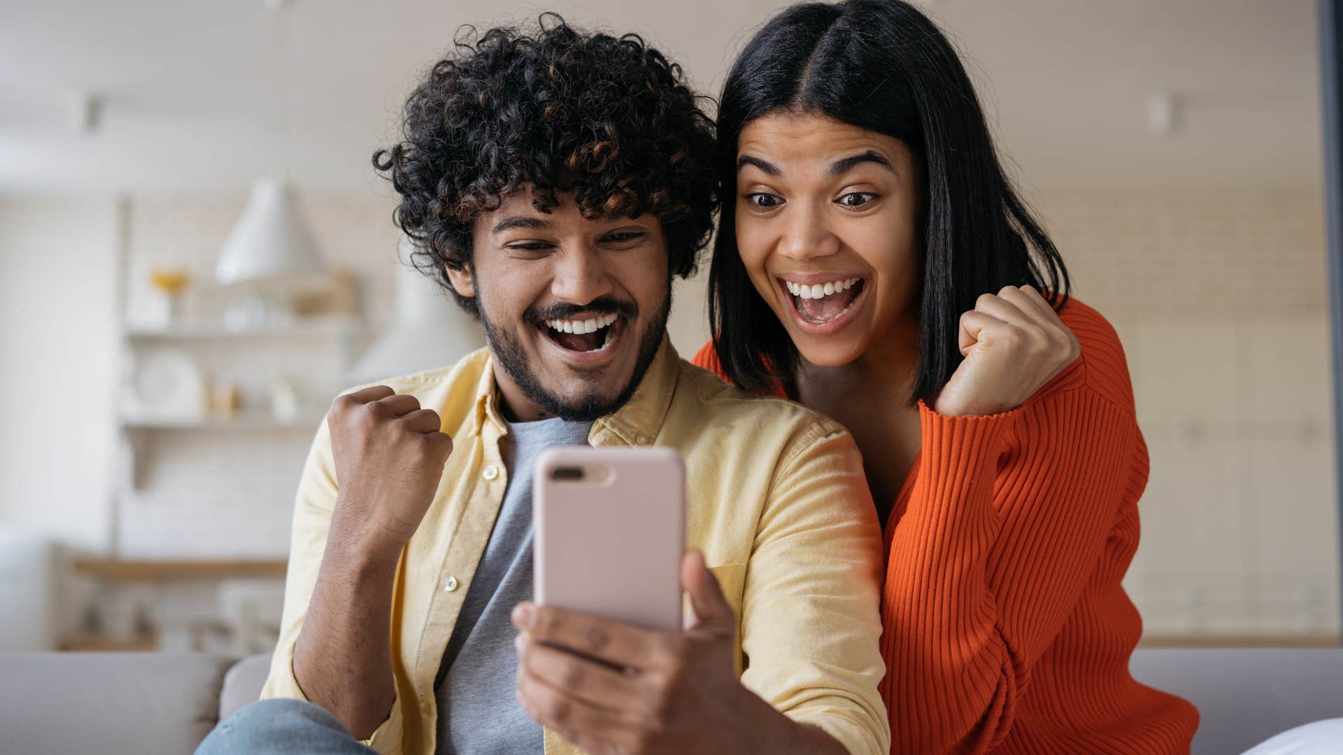 couple celebrating their small wins looking at a phone