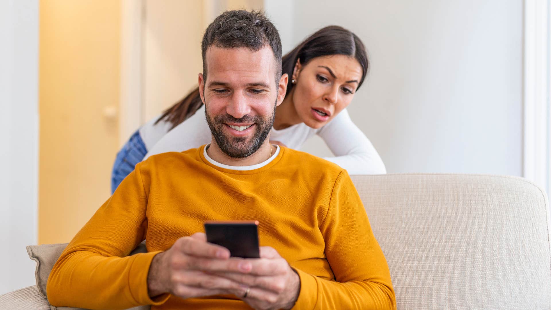 man cheating texting another woman while partner looks over his shoulder