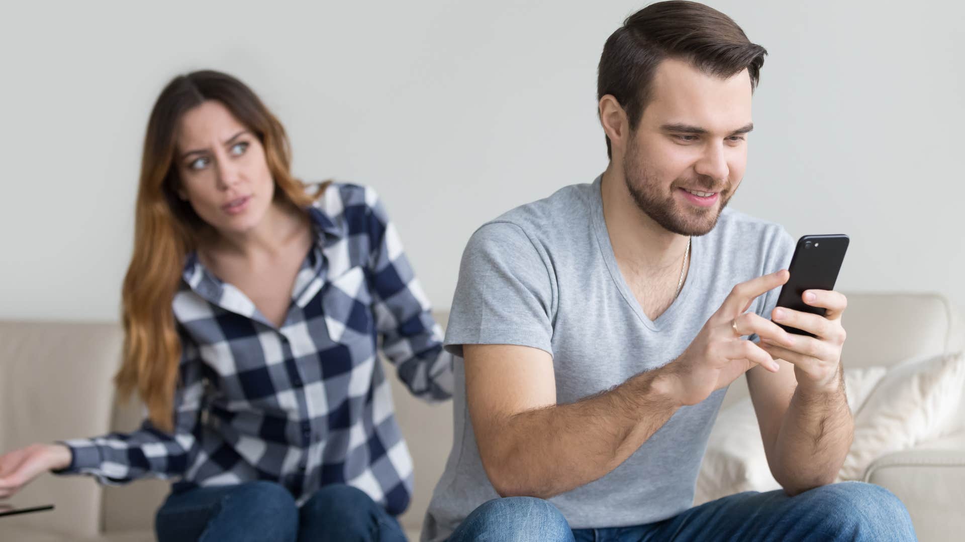 Man who speaks negatively about you texting on the couch.