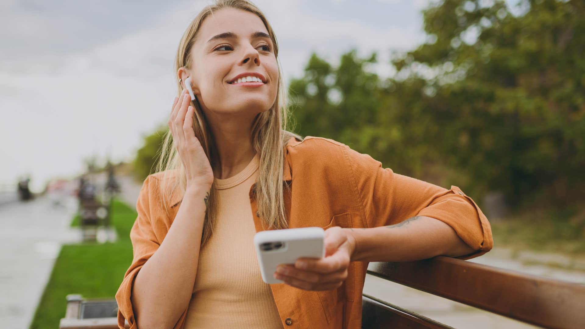 open-minded woman sitting outside listening to music