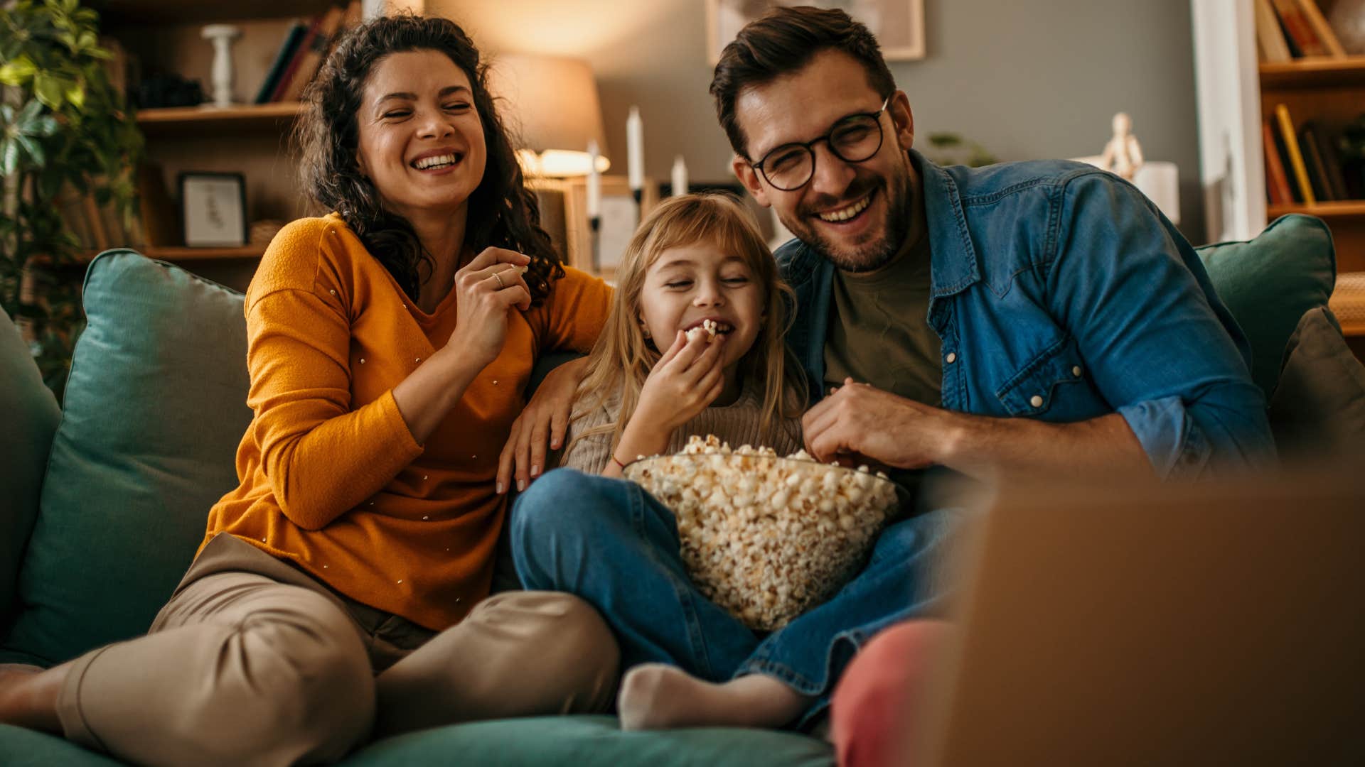Couple who owns a home sitting on the couch.