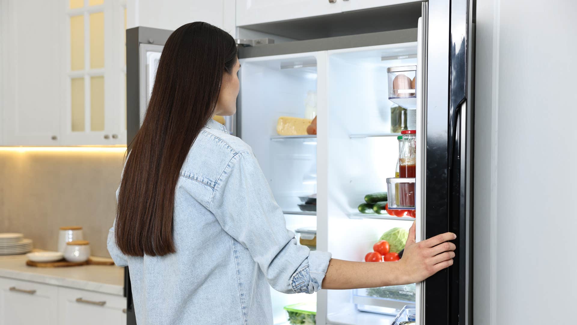 middle class woman opening fridge with ice maker and water dispenser