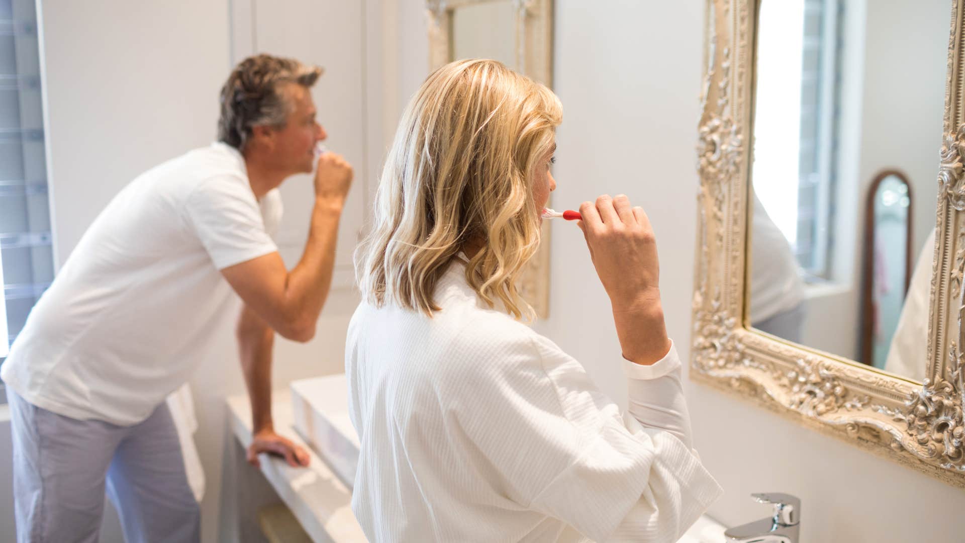 middle class couple brushing their teeth at their two sinks