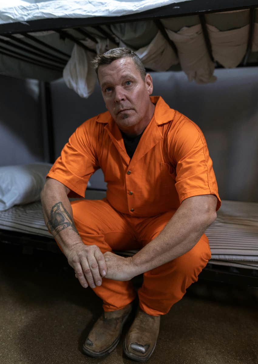 male prisoner sitting on cot in his cell