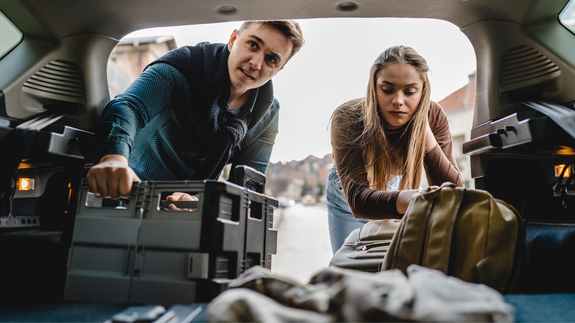man telling woman he has a system to the madness in his car trunk