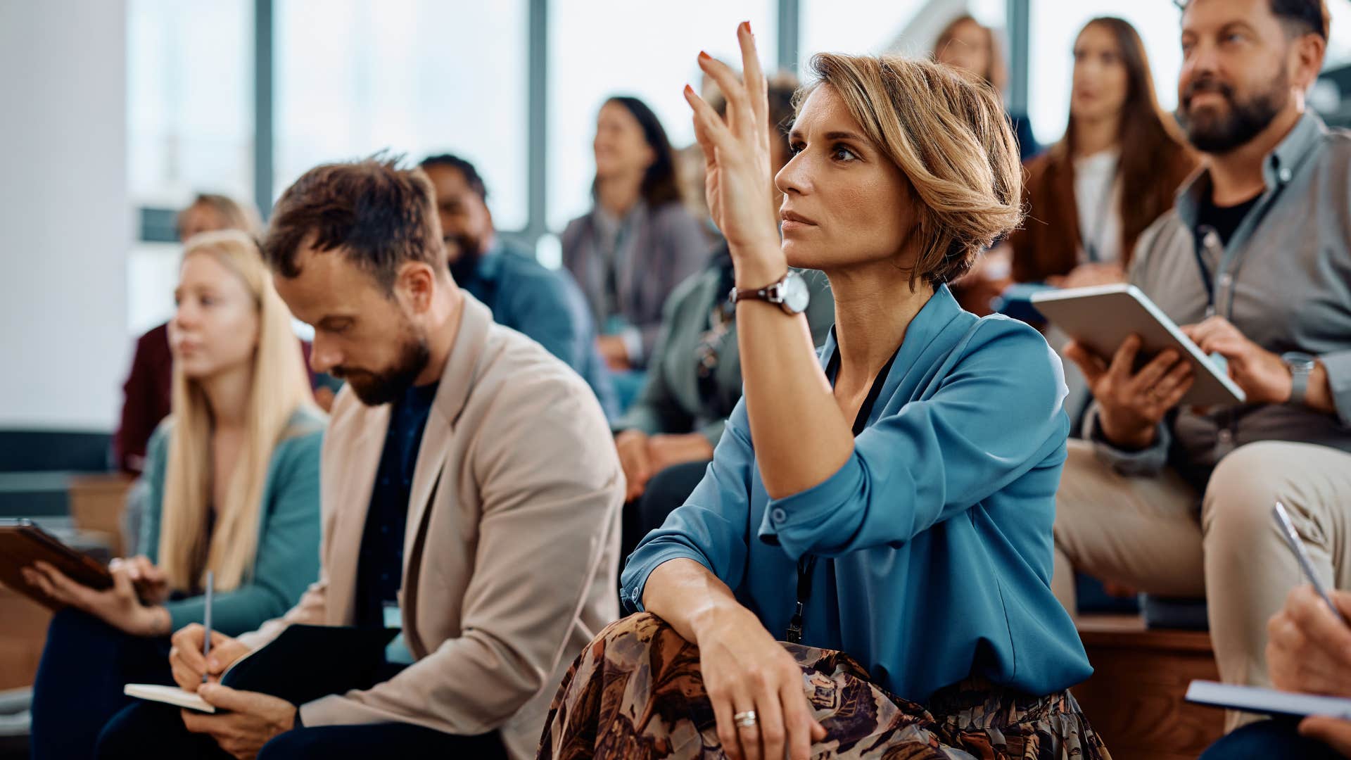woman raising hand and asking questions that were just answered