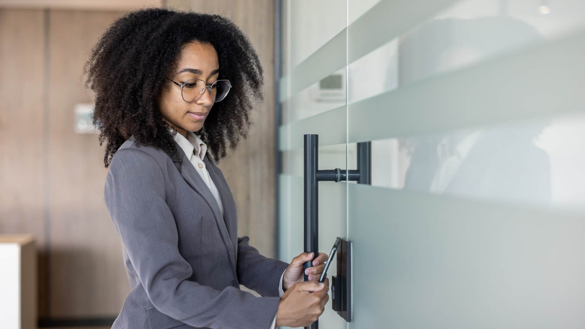 woman in gray suit pushes doors open clearly labeled pull