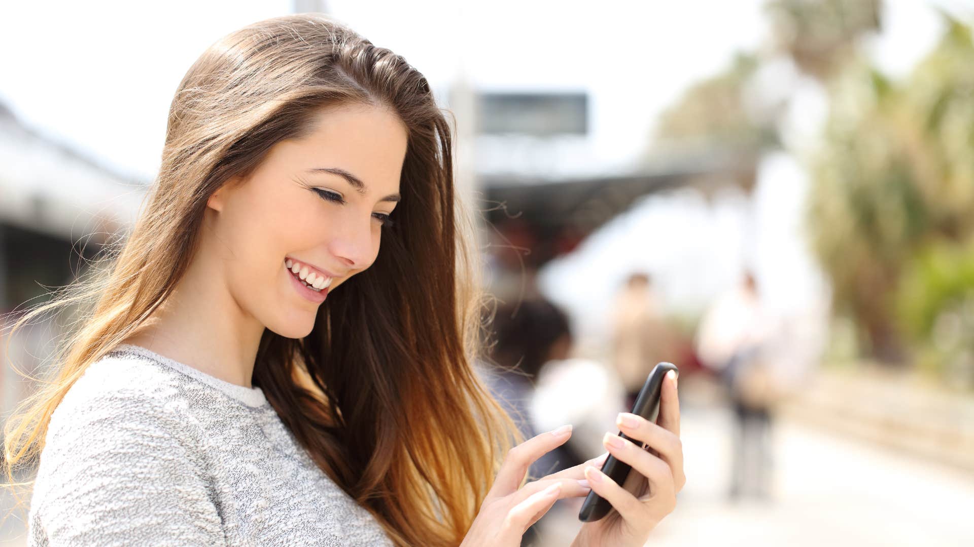 woman in grey talks loudly on speakerphone in public