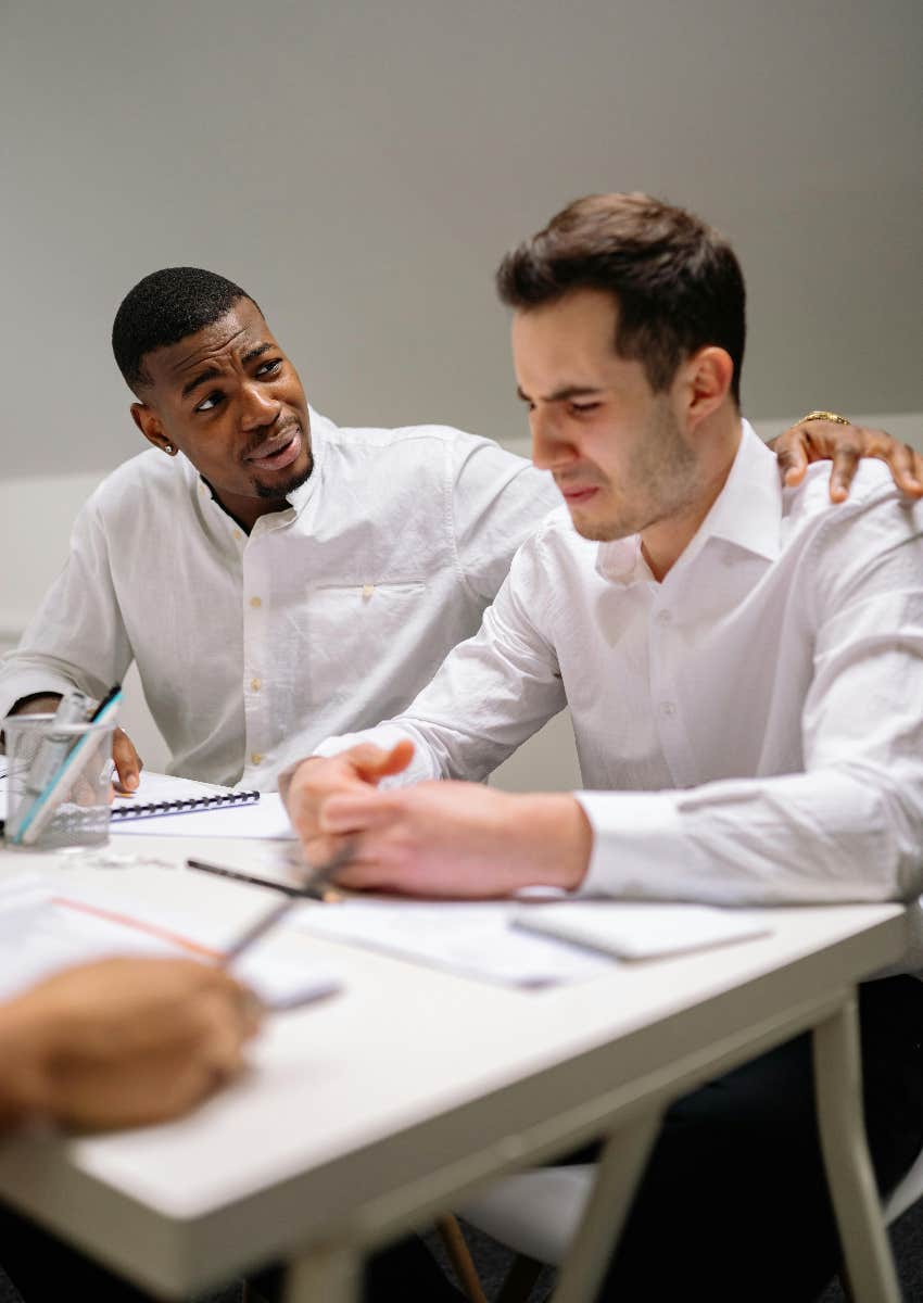man crying at work being comforted by his co-worker