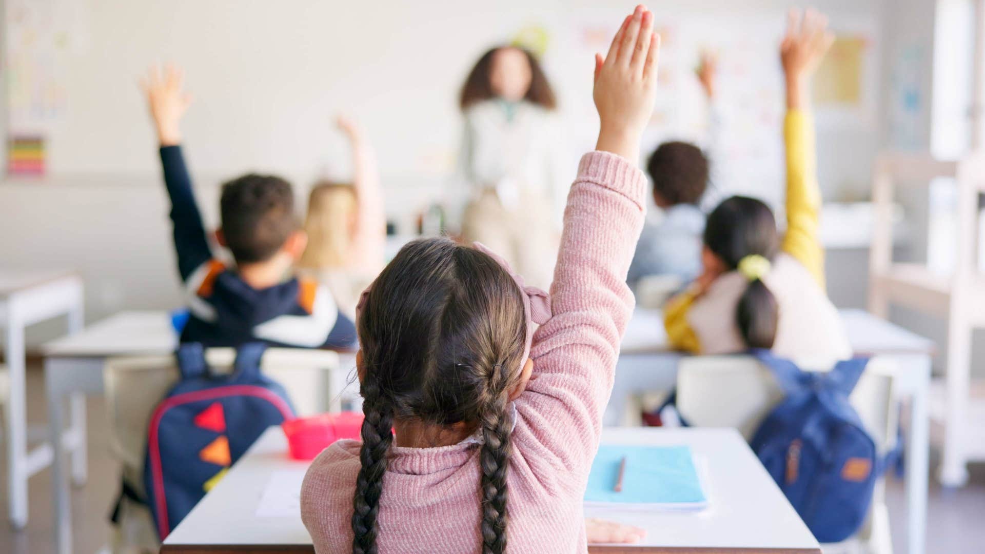 students raising their hands in class