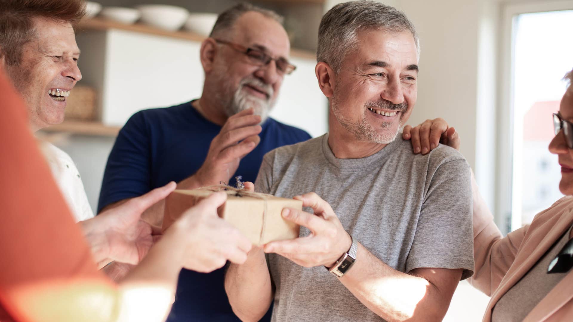 man smiling around friends during his surprise party