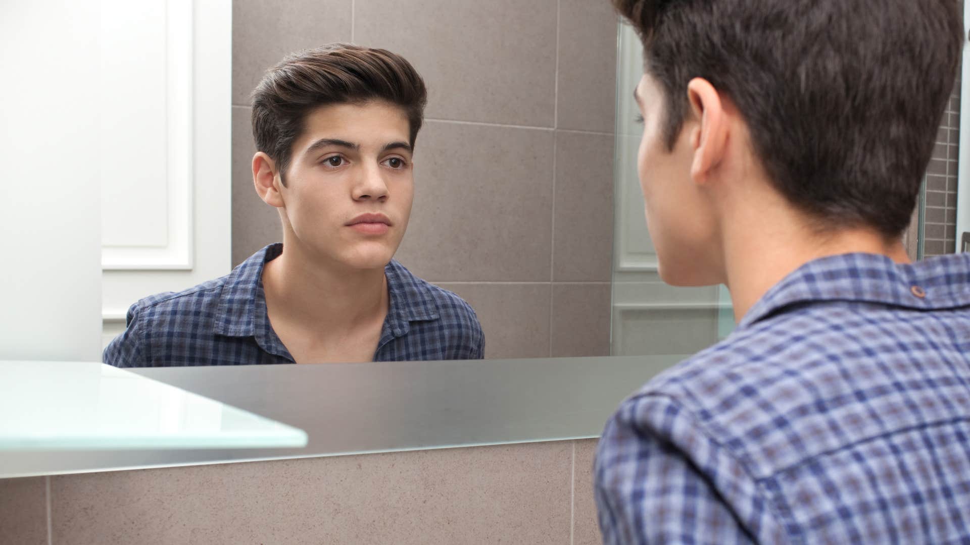 gen z man who believes confidence comes solely from looks staring at a mirror