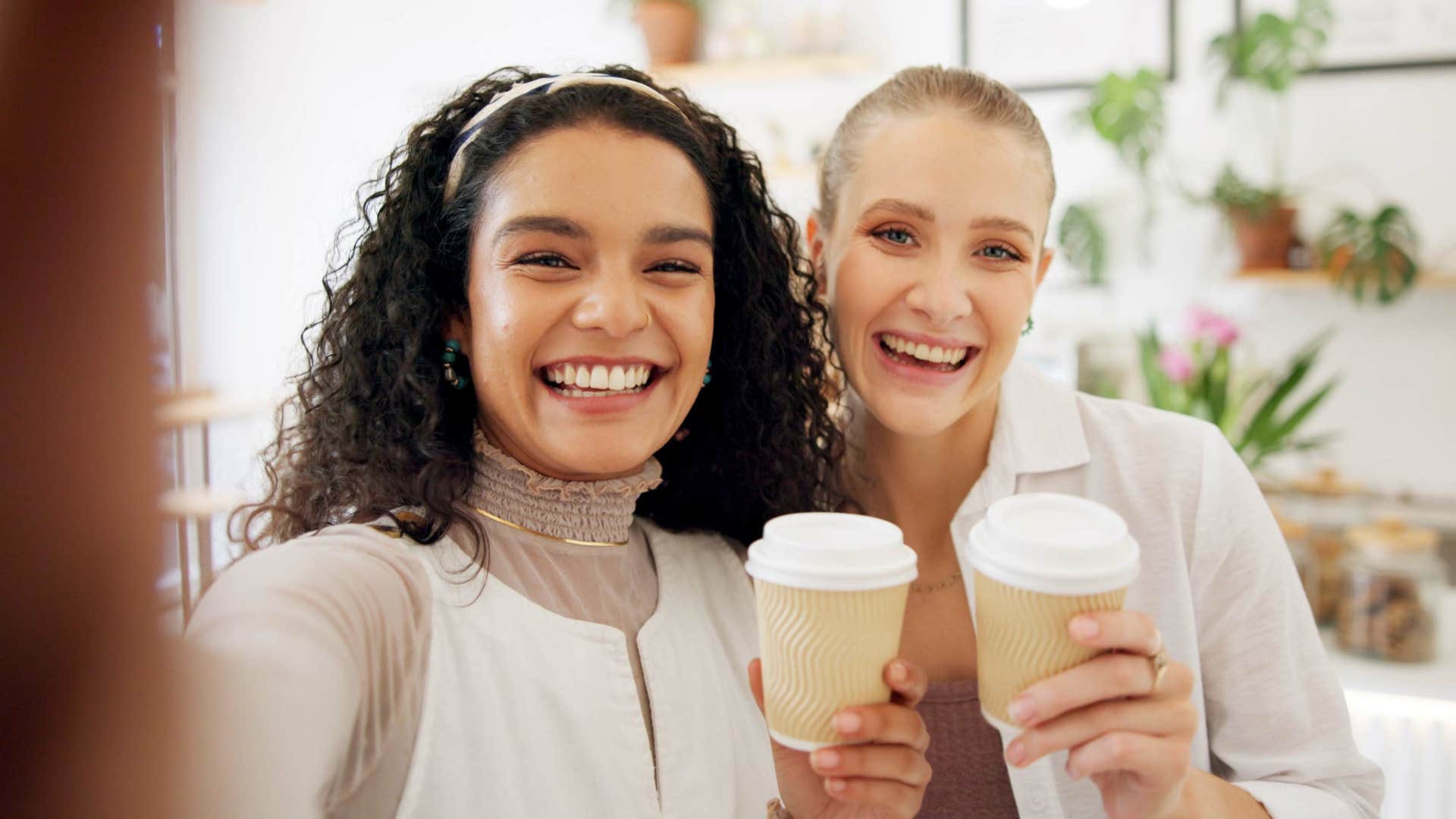 two women smiling drinking coffee happy