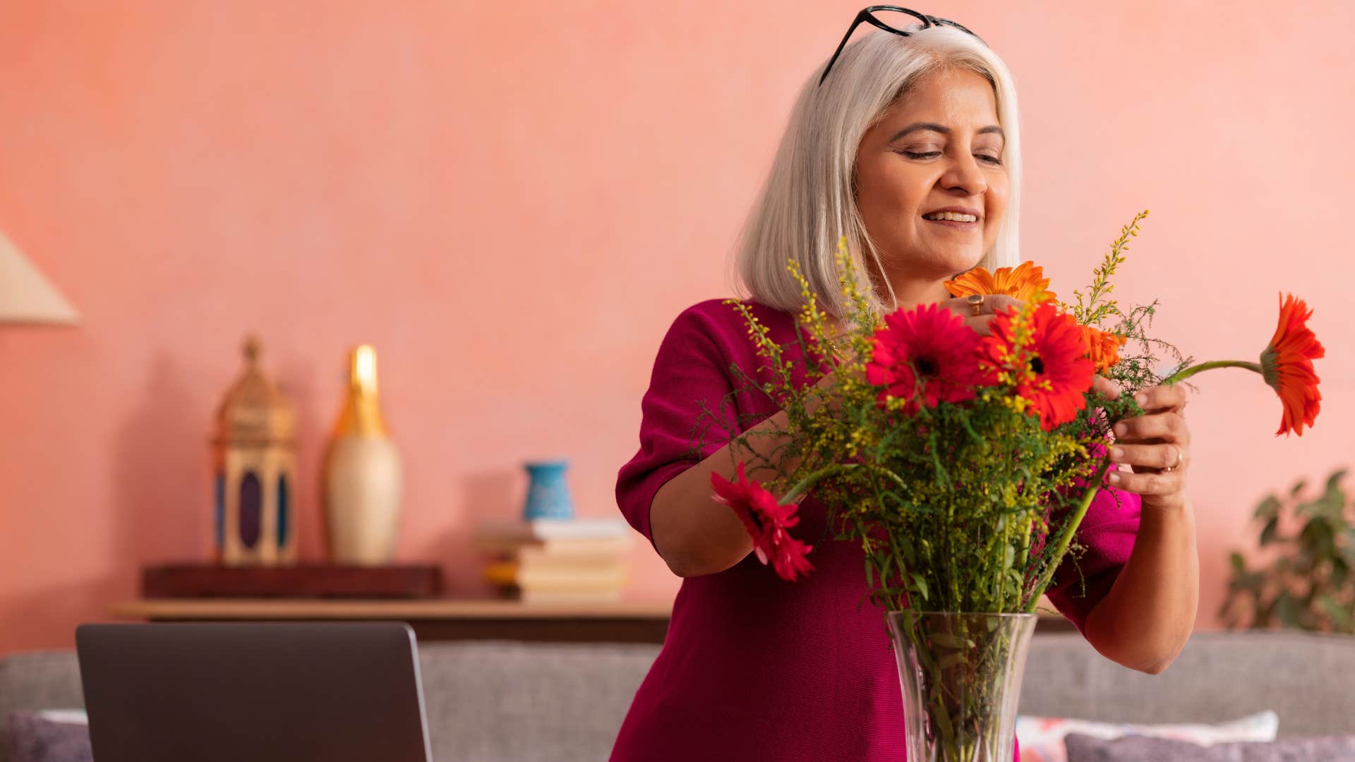 Woman with customized decor at home smiling with flowers.