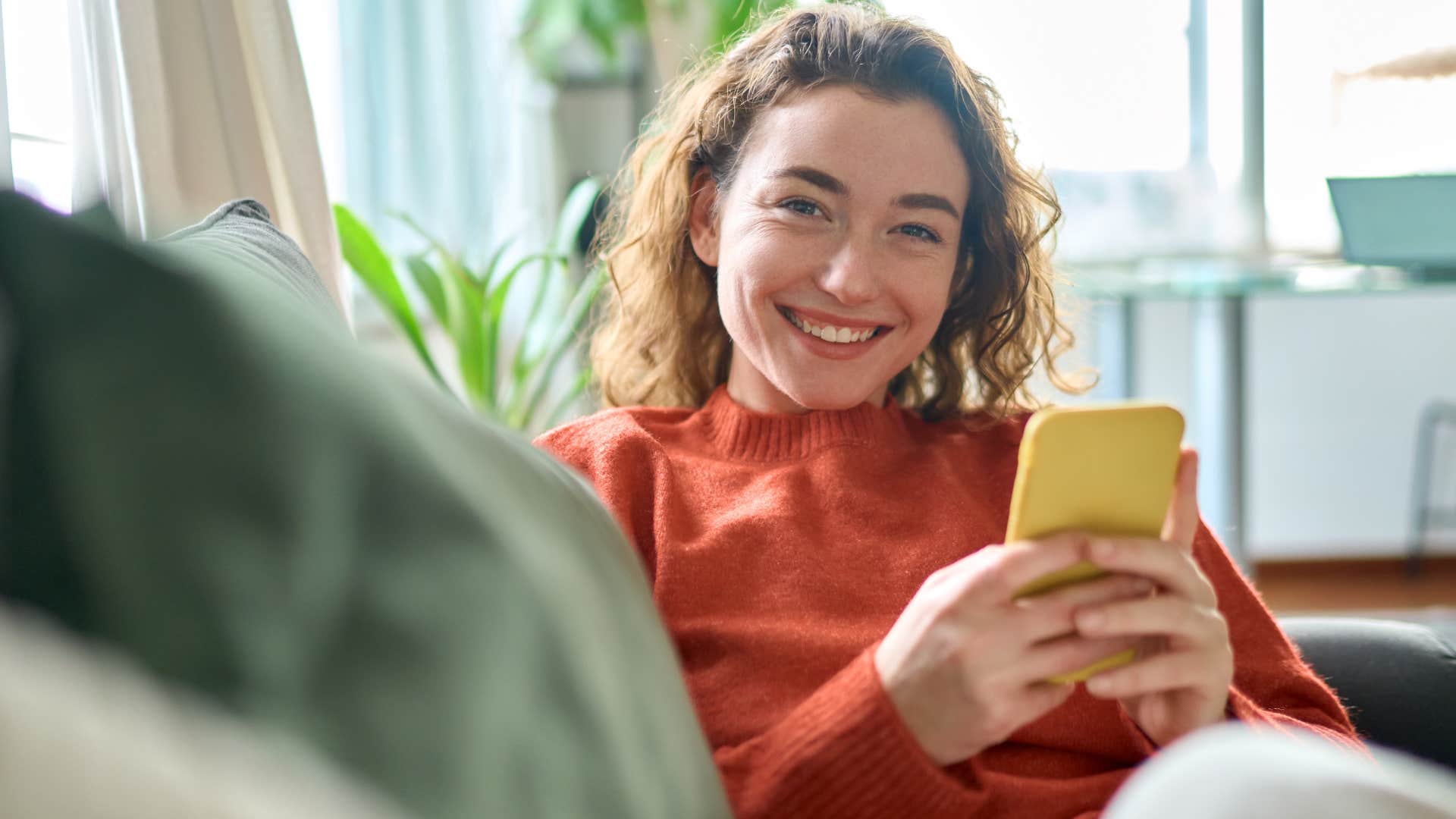 Woman smiling in a home with a "lived in" and welcoming aesthetic.