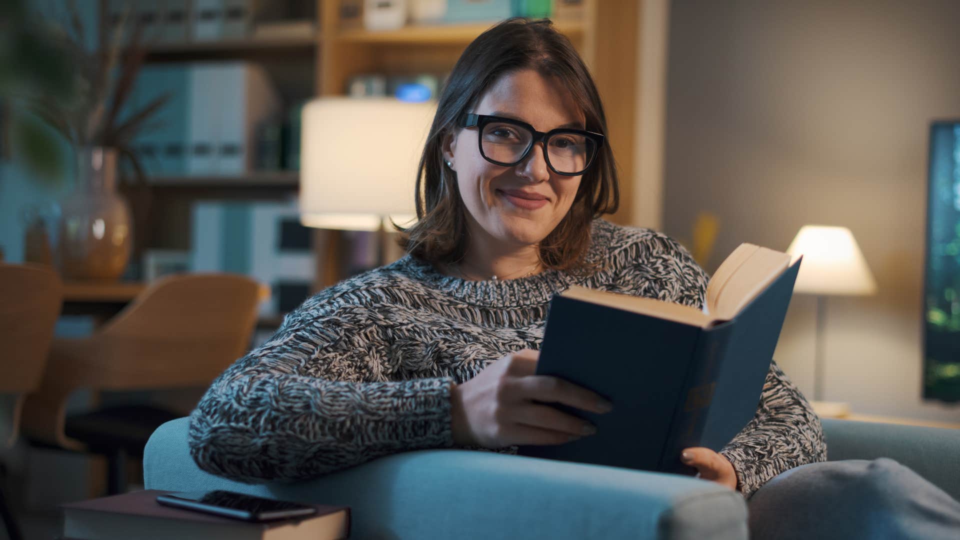 Woman smiling with her personal book collection at home.