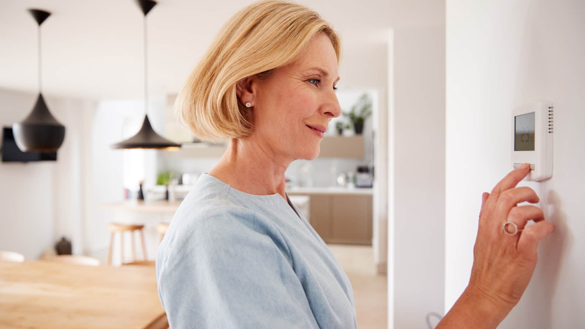 woman adjusting thermostat at home