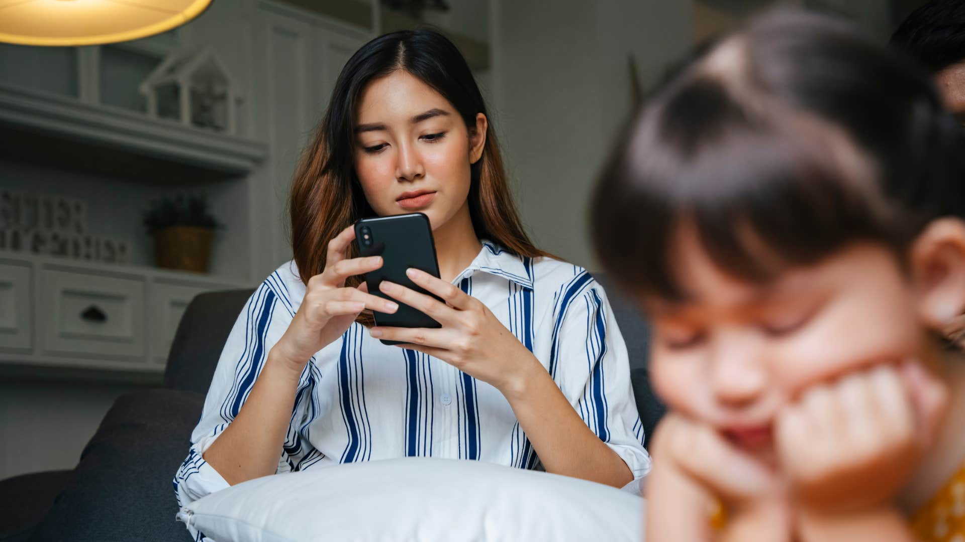 woman on her phone half listening to frustrated daughter