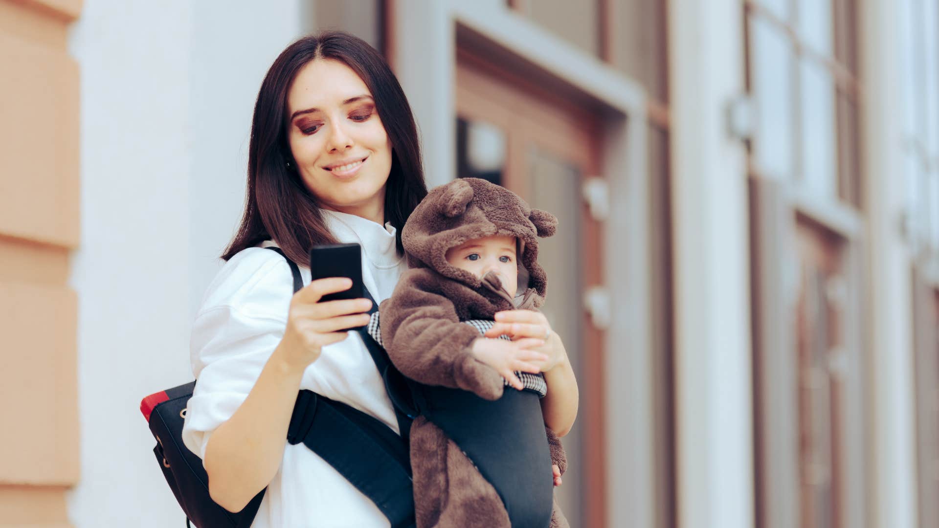 mom walking and scrolling while holding child