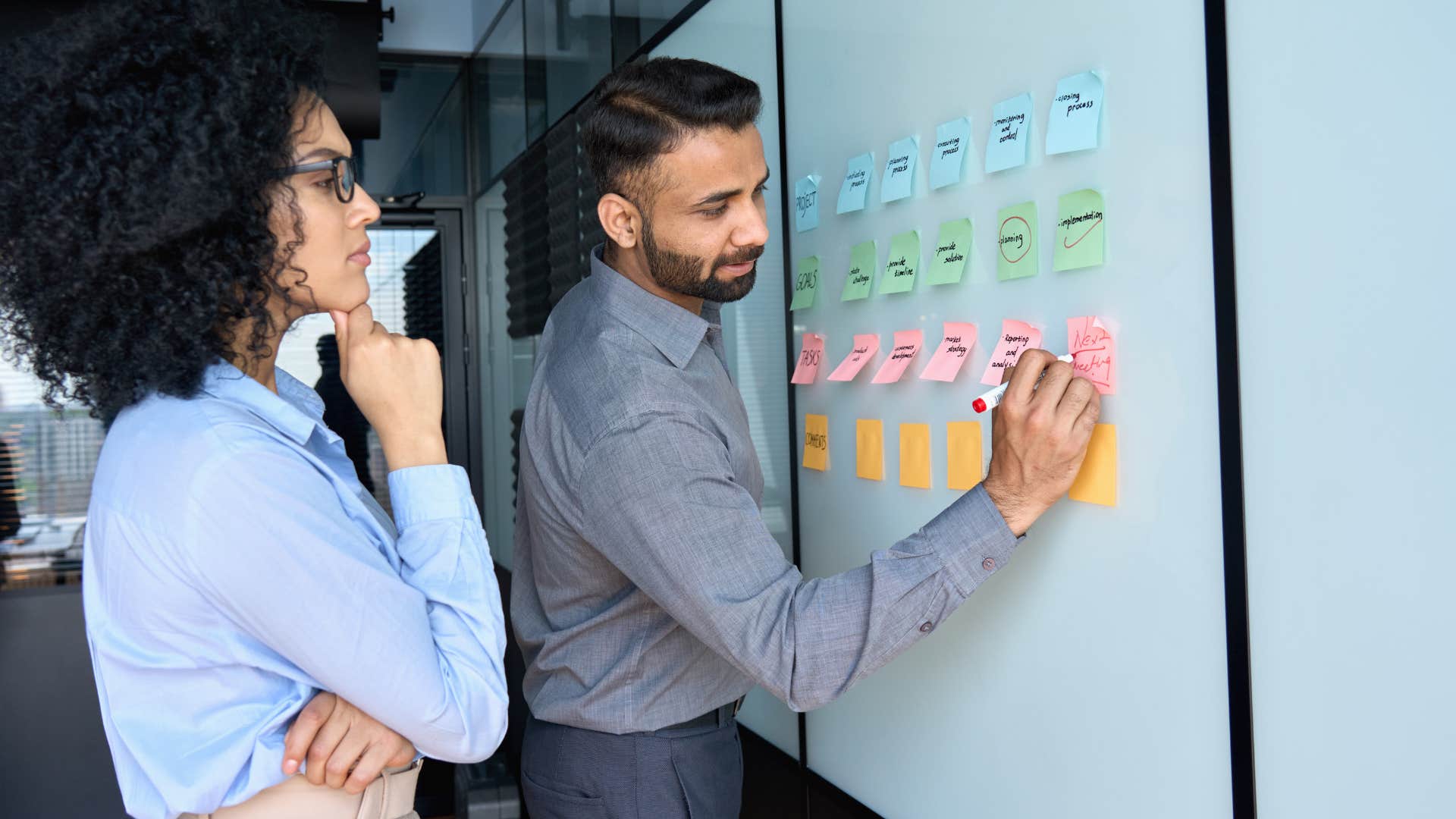 woman working with groups of people as they write on board