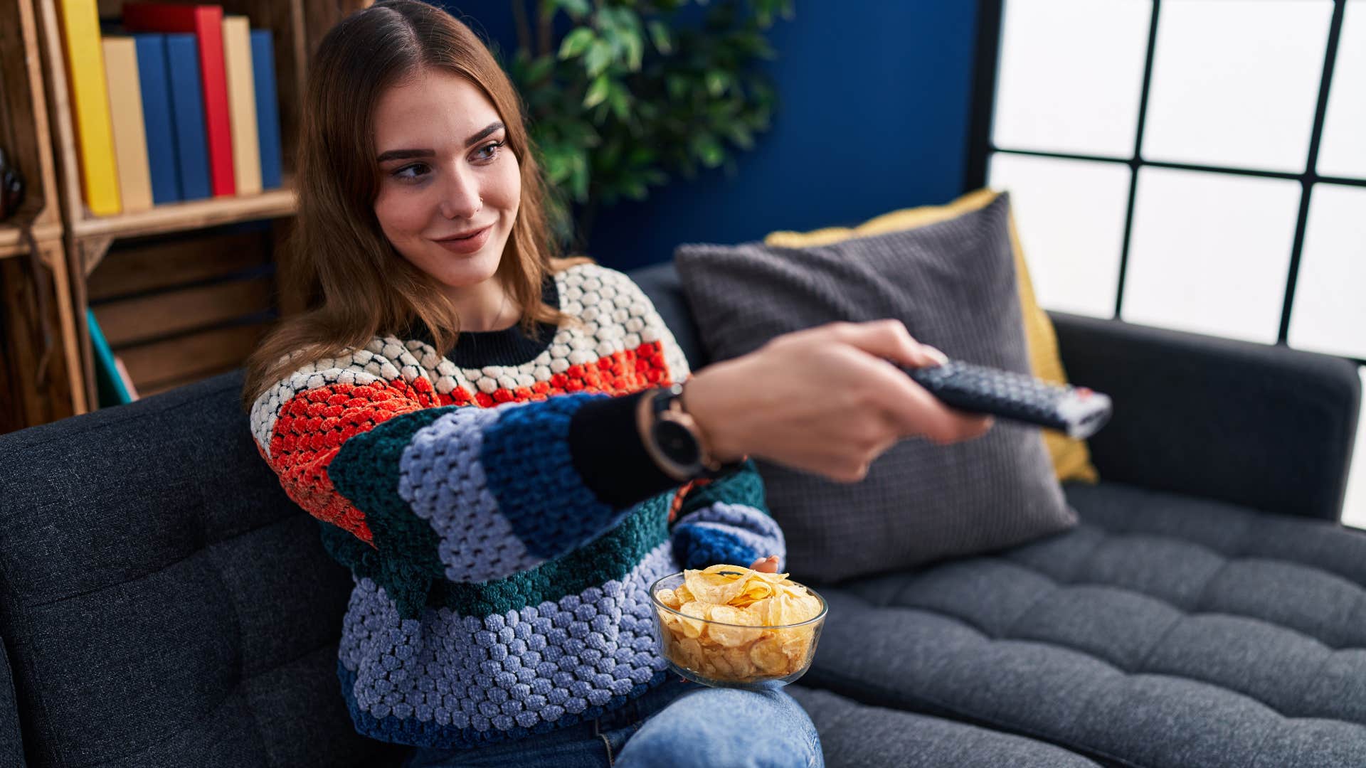woman watching reality tv with remote control and popcorn