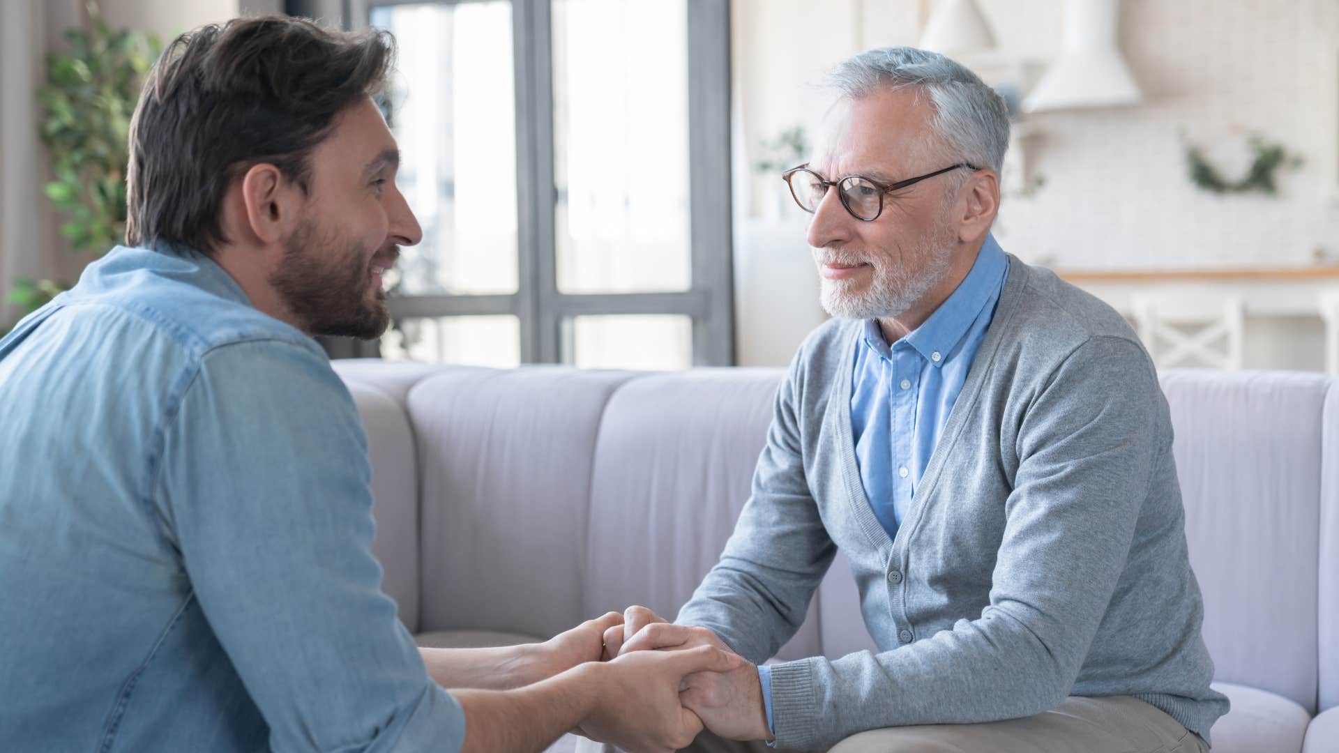 man giving to his older father holding his hands caringly