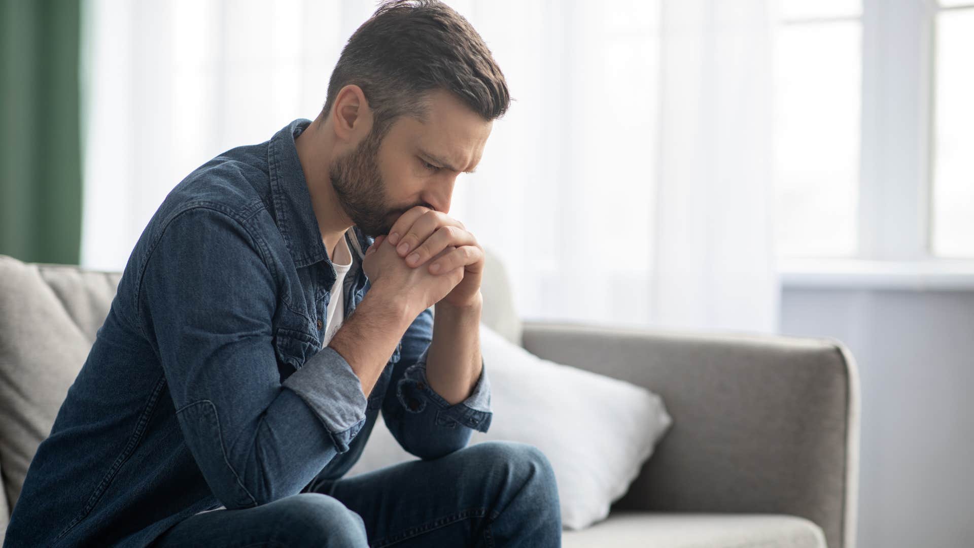 upset extroverted man sitting in an empty room by himself