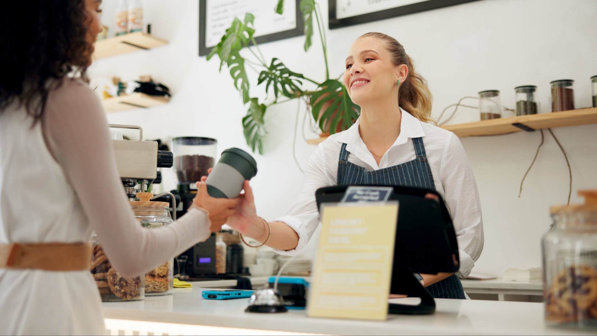 barista handing customer cup of coffee
