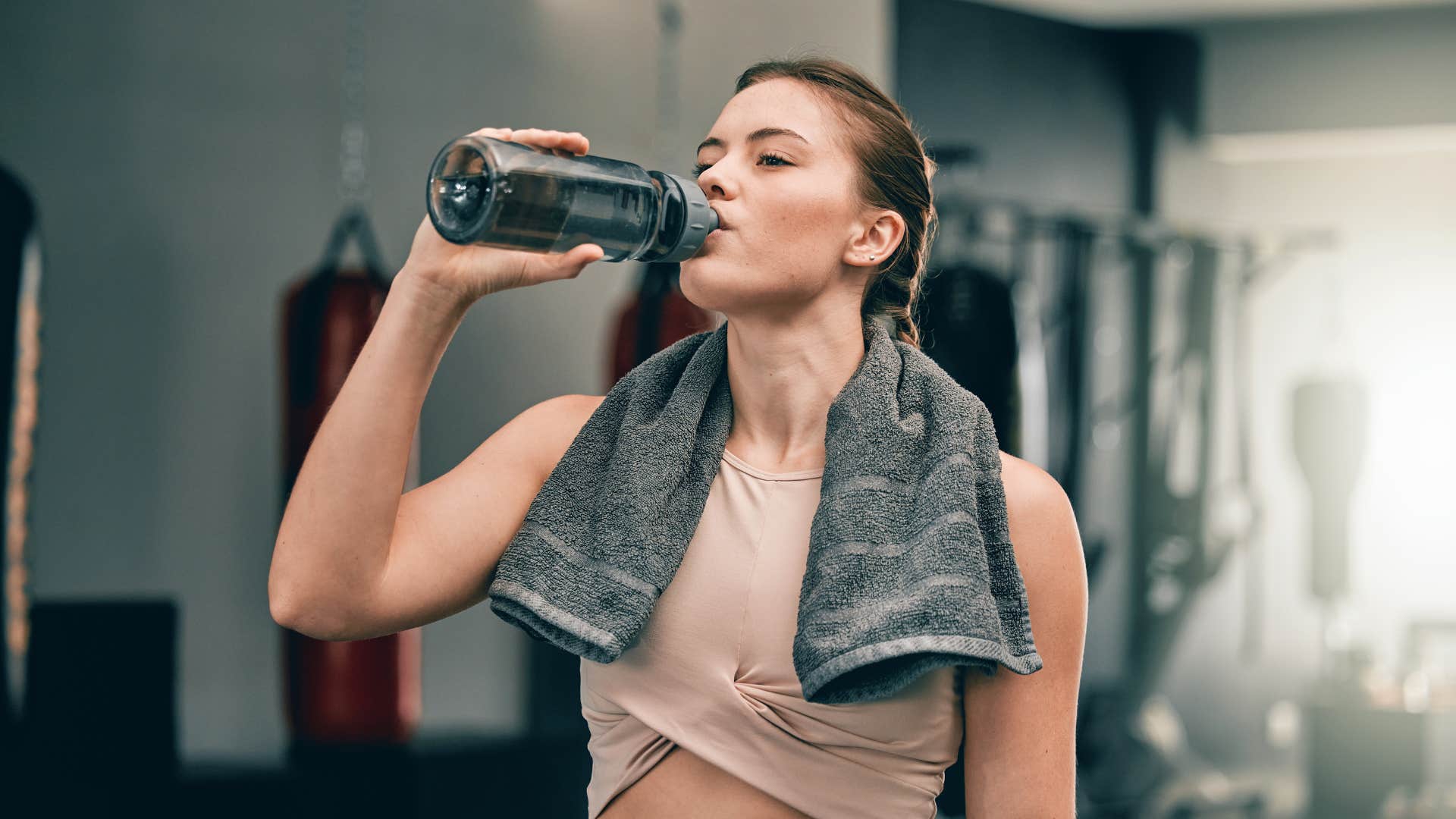 woman drinking water out of reusable bottle