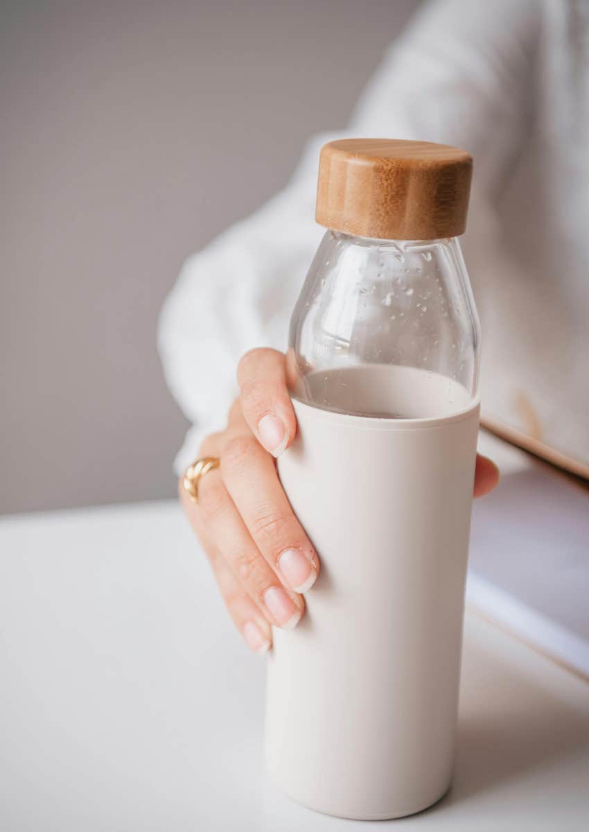 woman's hand picking up a reusable water bottle