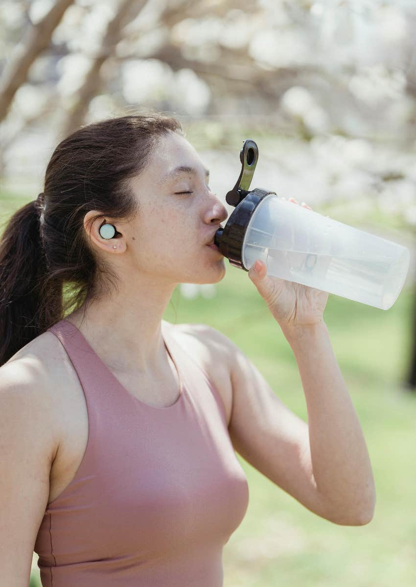 woman drinking out of a reusable water bottle