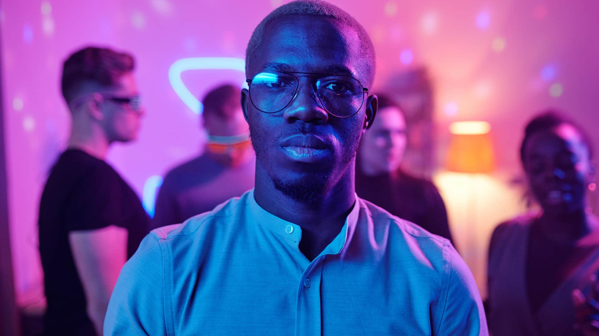 introverted man standing in crowded party looking annoyed