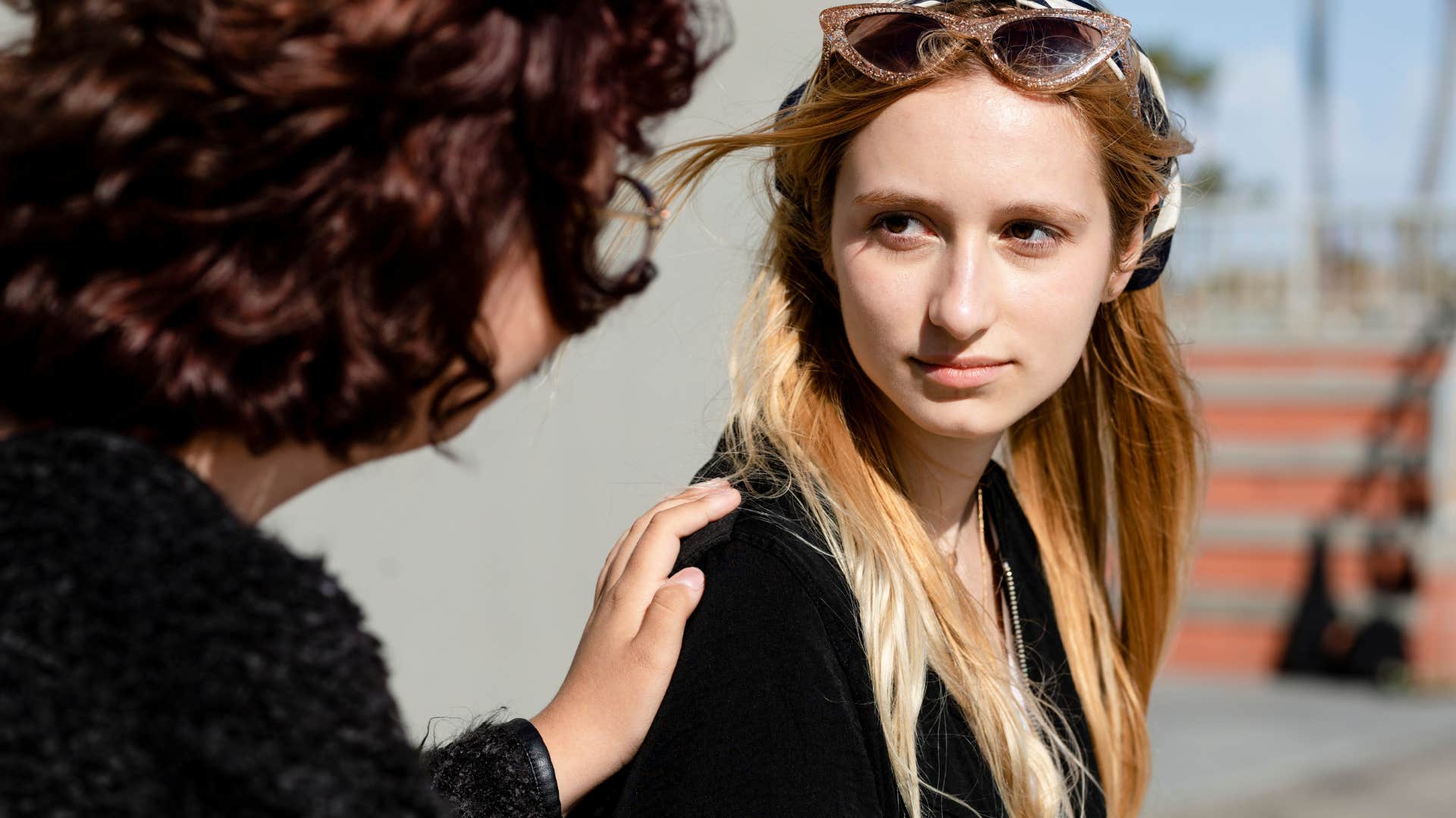 woman smiling at friend comforting her outside