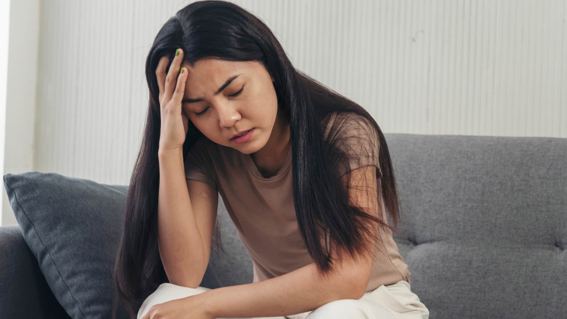 Woman who doesn't feel heard holding her head at home.