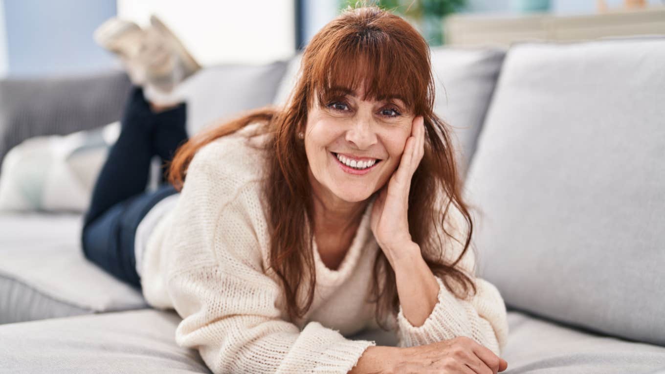 older woman smiling relaxing at home laying on the couch
