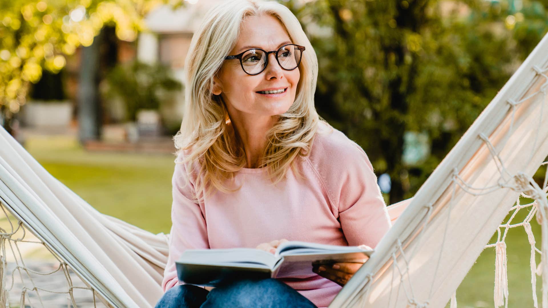 introverted older woman reading in a hammock