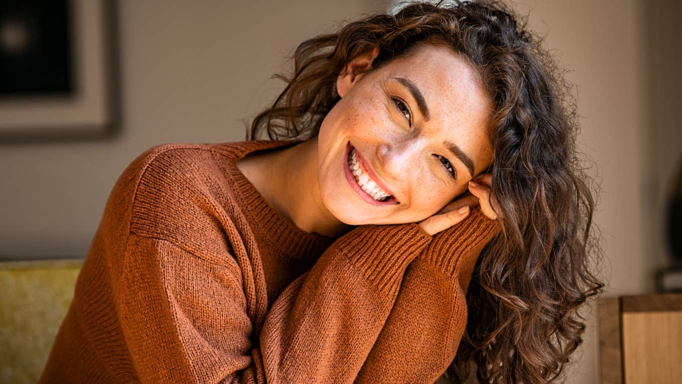 Smiling young woman relaxing at home, illustrating the beautiful secrets of people who are joyfully single and whole