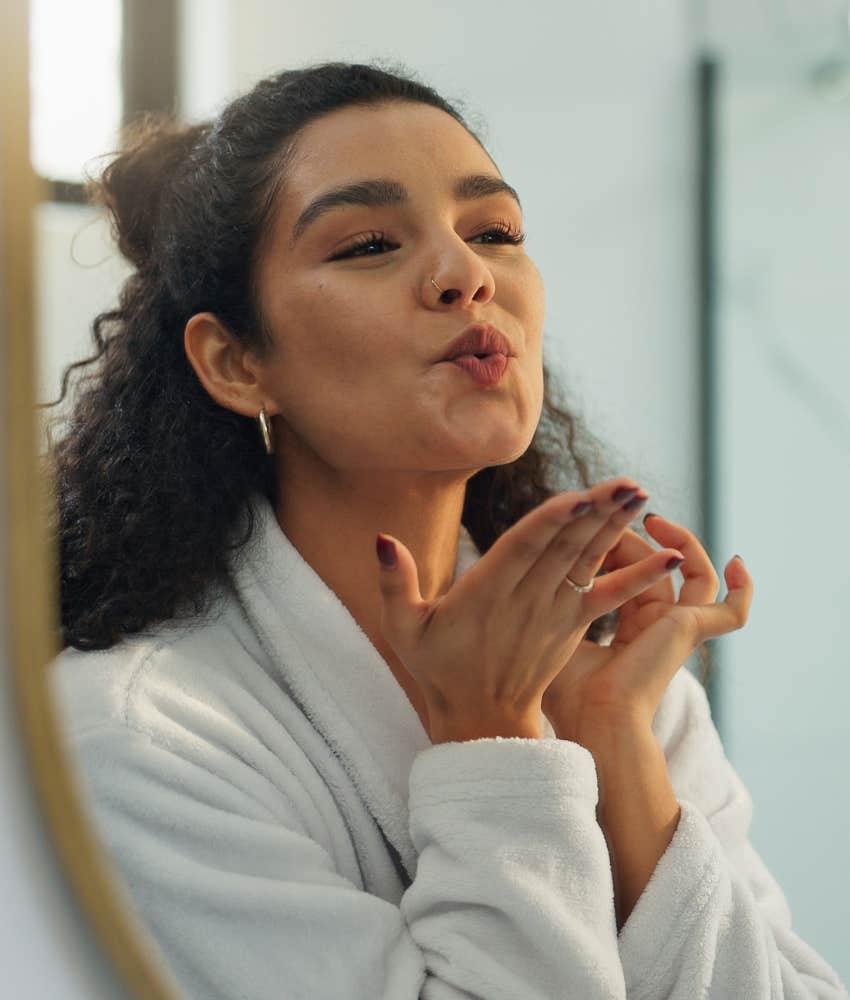 Person blows kiss in mirror to uplift themselves