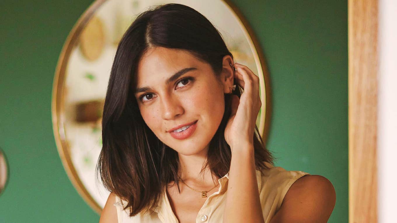 Beautiful Truths About What It Actually Means To Love Someone From The Depths Of Your Soul  Smiling woman in sleeveless shirt touching her hair, embodying the warmth and beauty of soulful, deep love