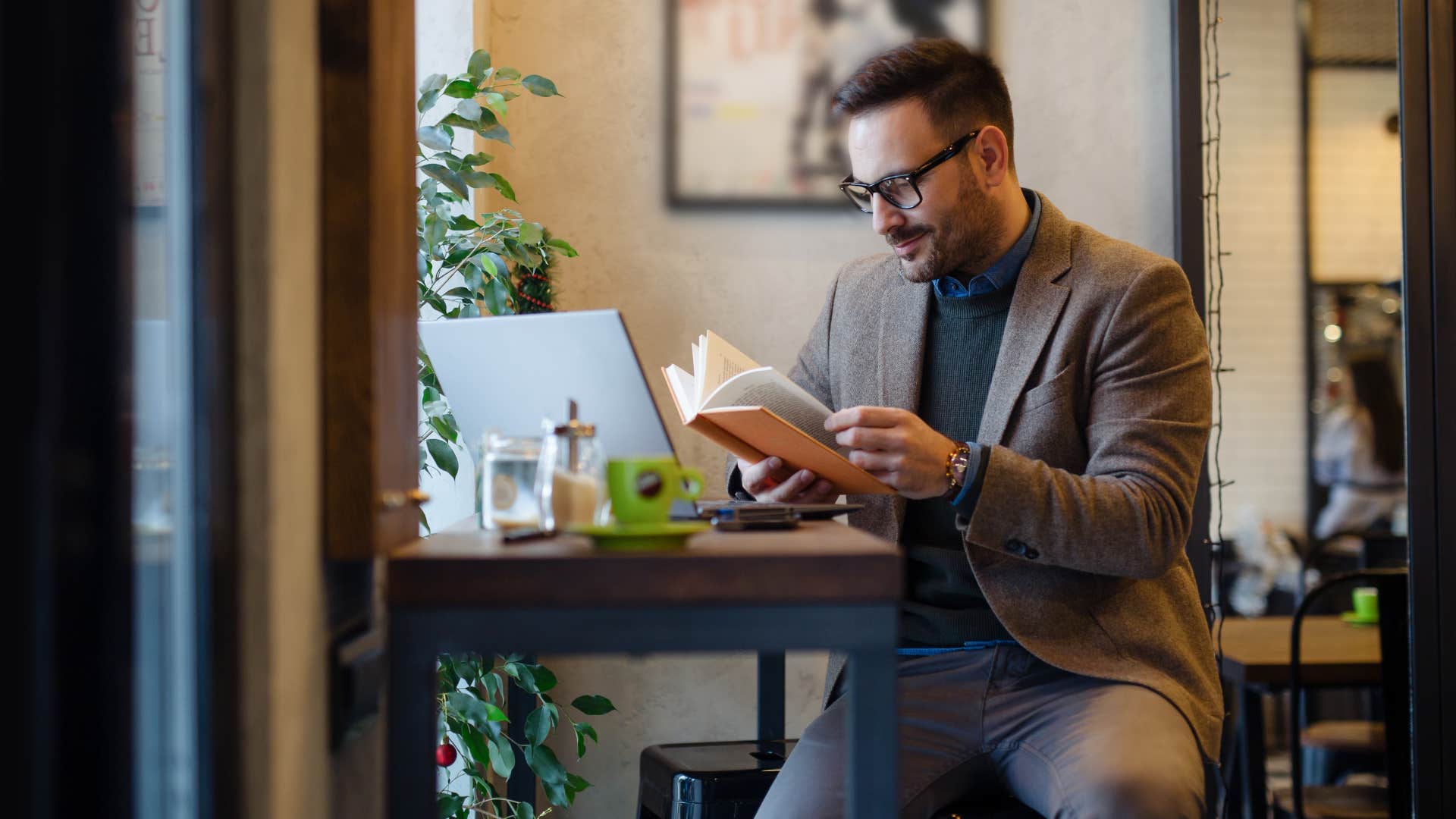 man reading book in cafe