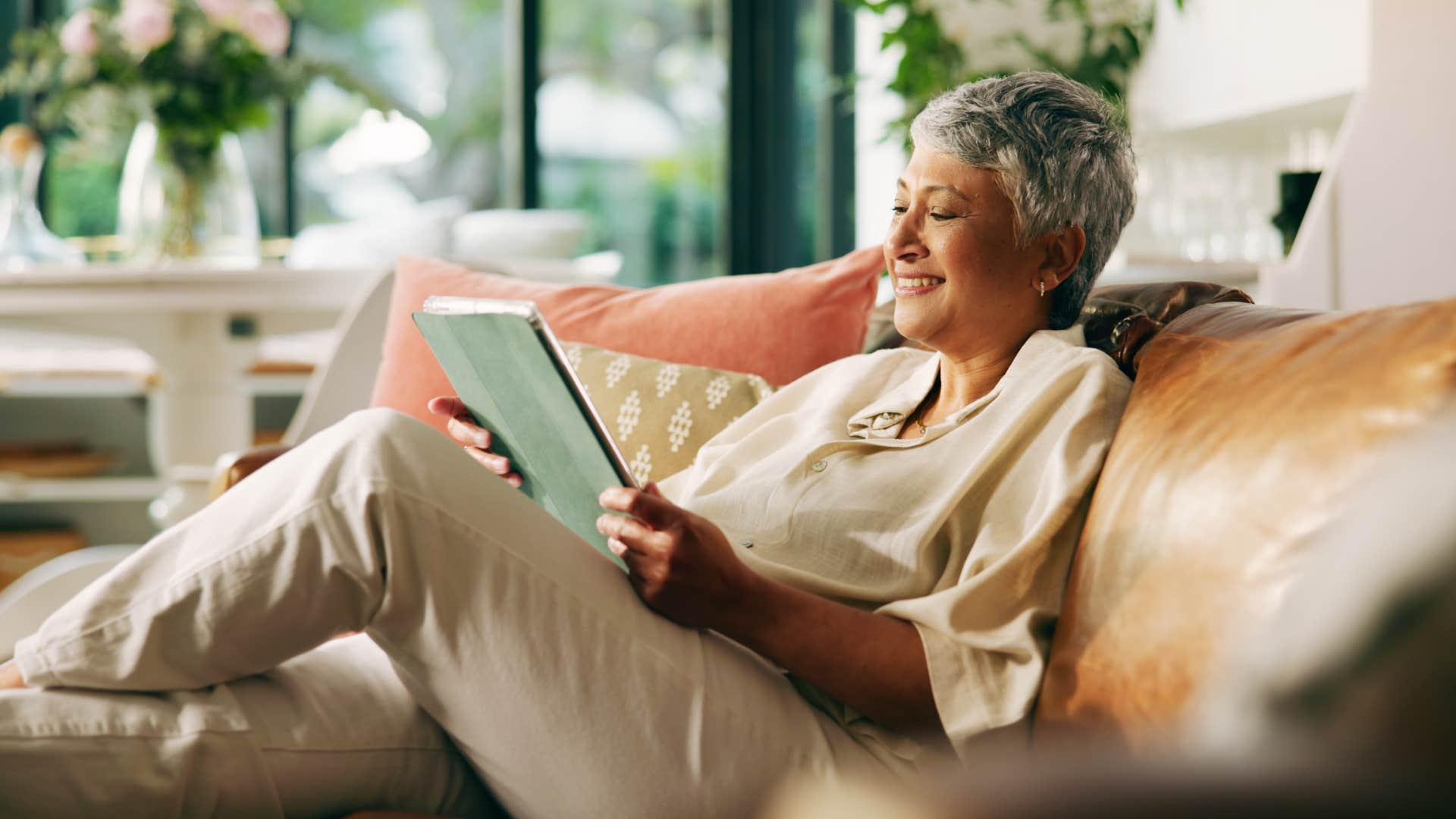older woman reading book on sofa to escape drama