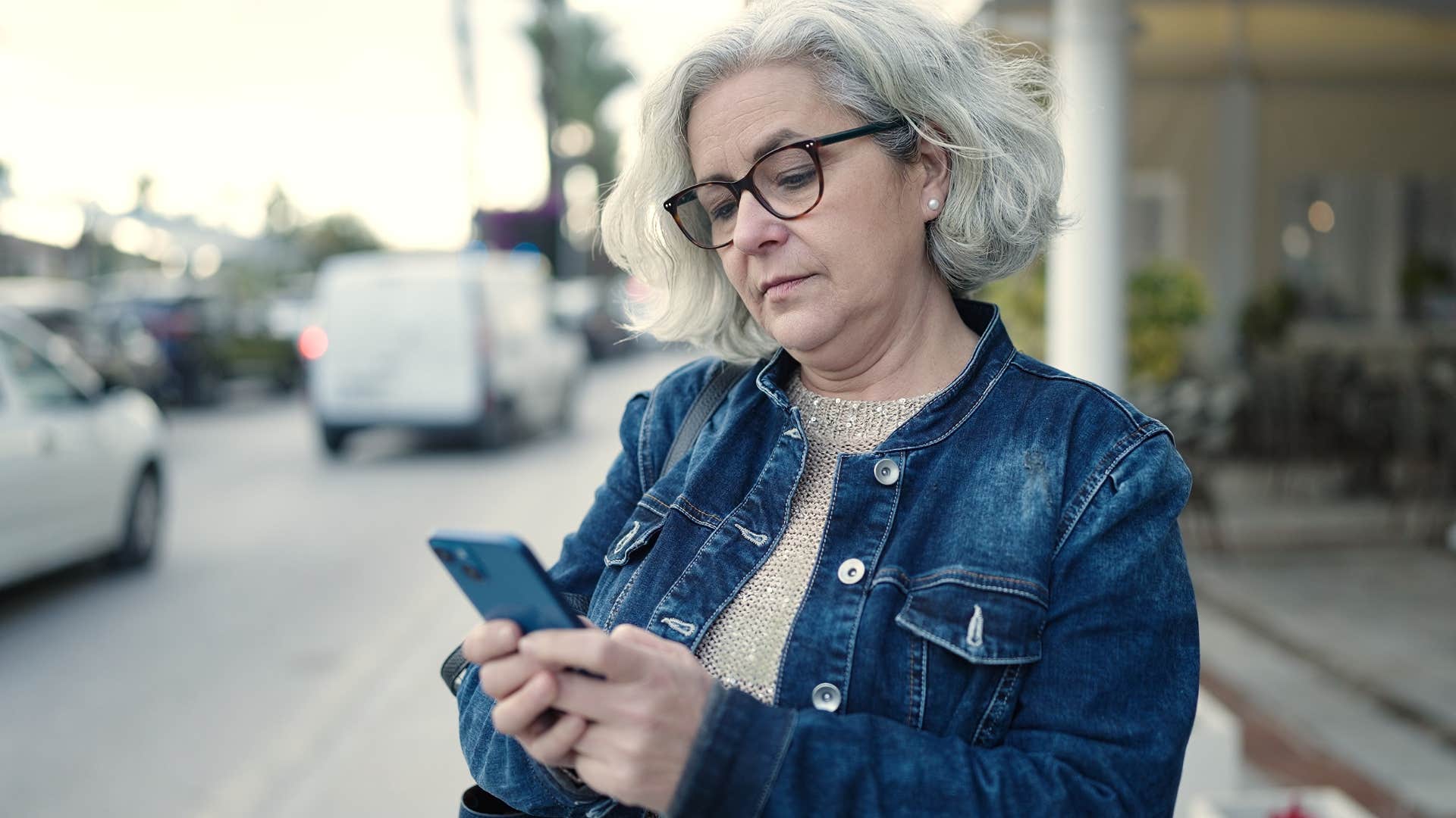 Woman texting "K" on her phone outside.