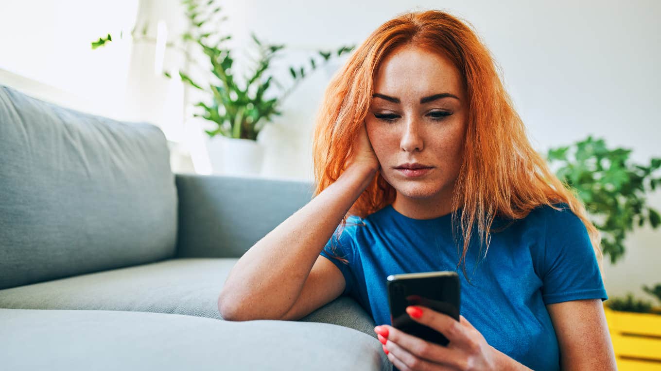 deeply unhappy woman looking at her phone