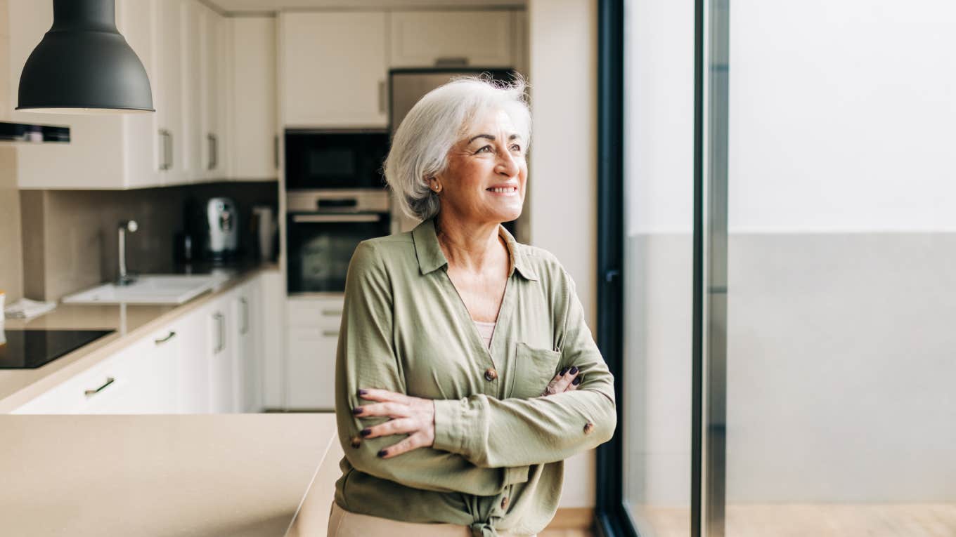 Every Generation Has This Treasured Item In Their Home That They Want To Use Daily, But Actually Hardly Ever Touch older woman standing in kitchen looking out window