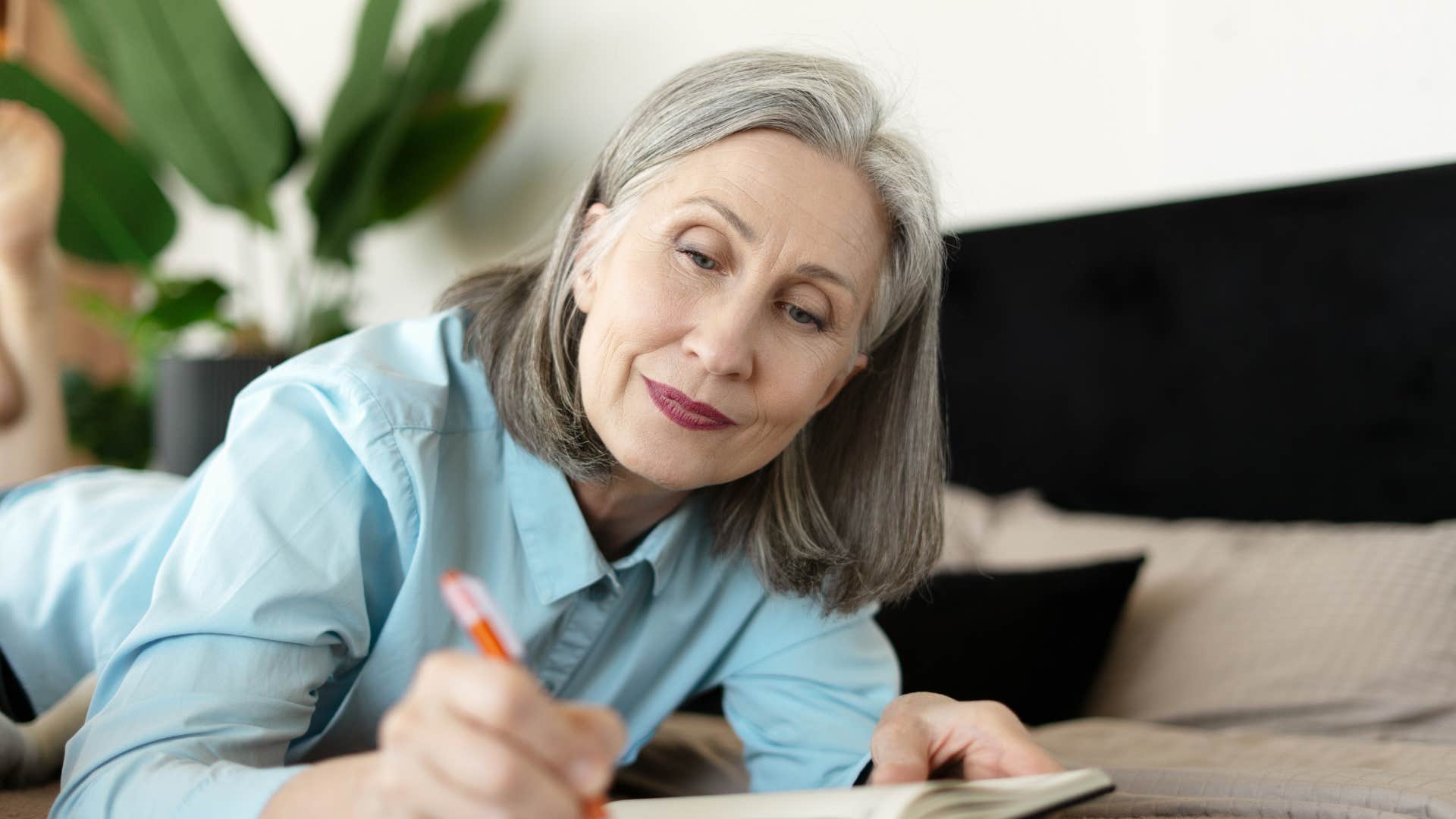 woman in blue shirt journaling or writing their thoughts