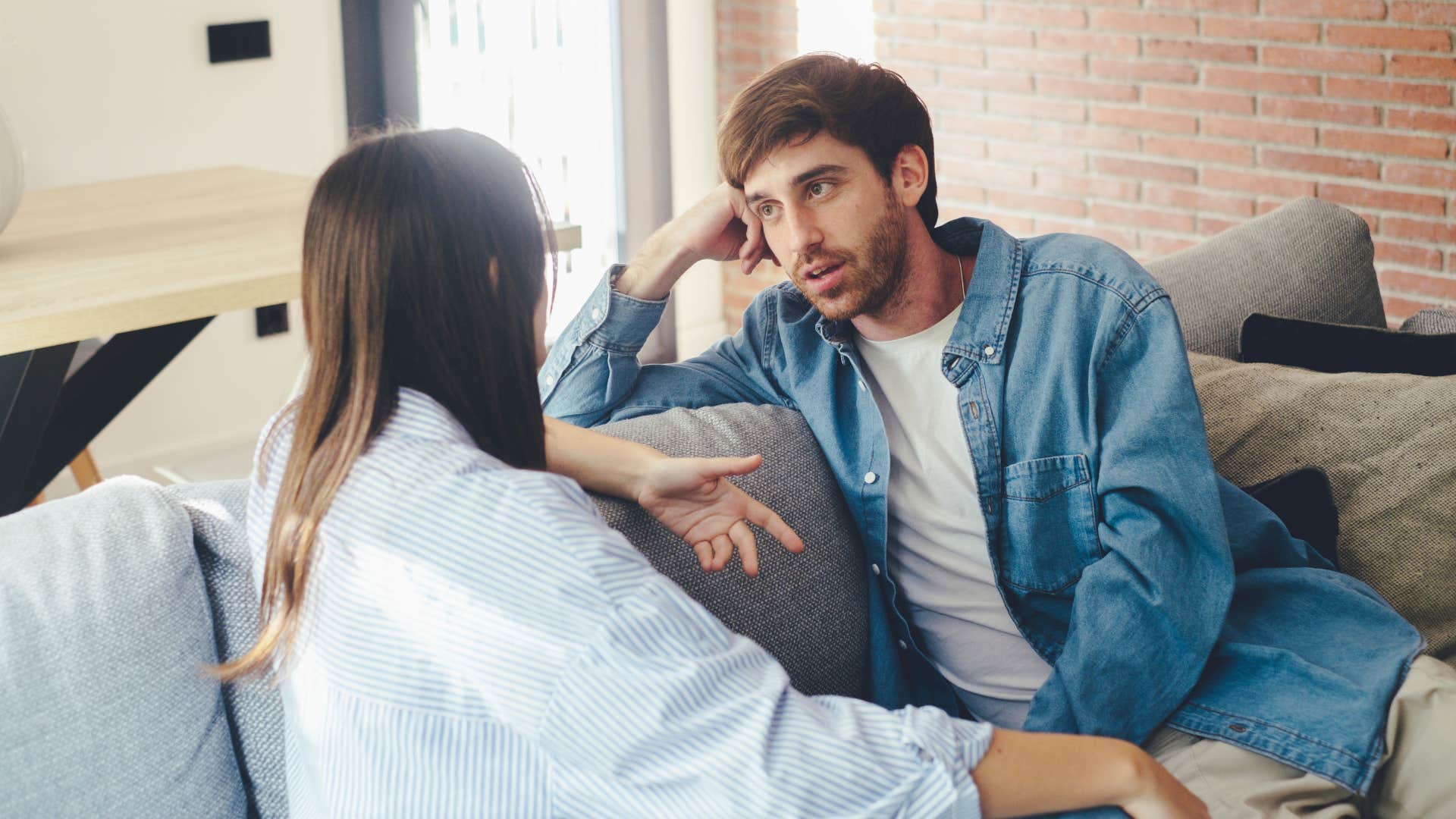 couple talking to one another on the couch as they prioritize meaningful conversation