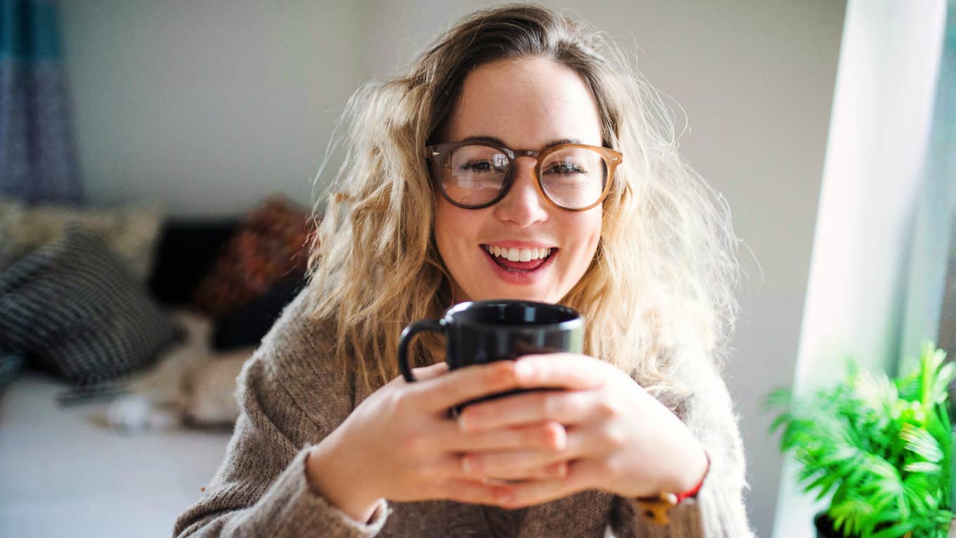 Happy woman holding coffee, illustrating daily habits that help people age slower and live happier, healthier lives
